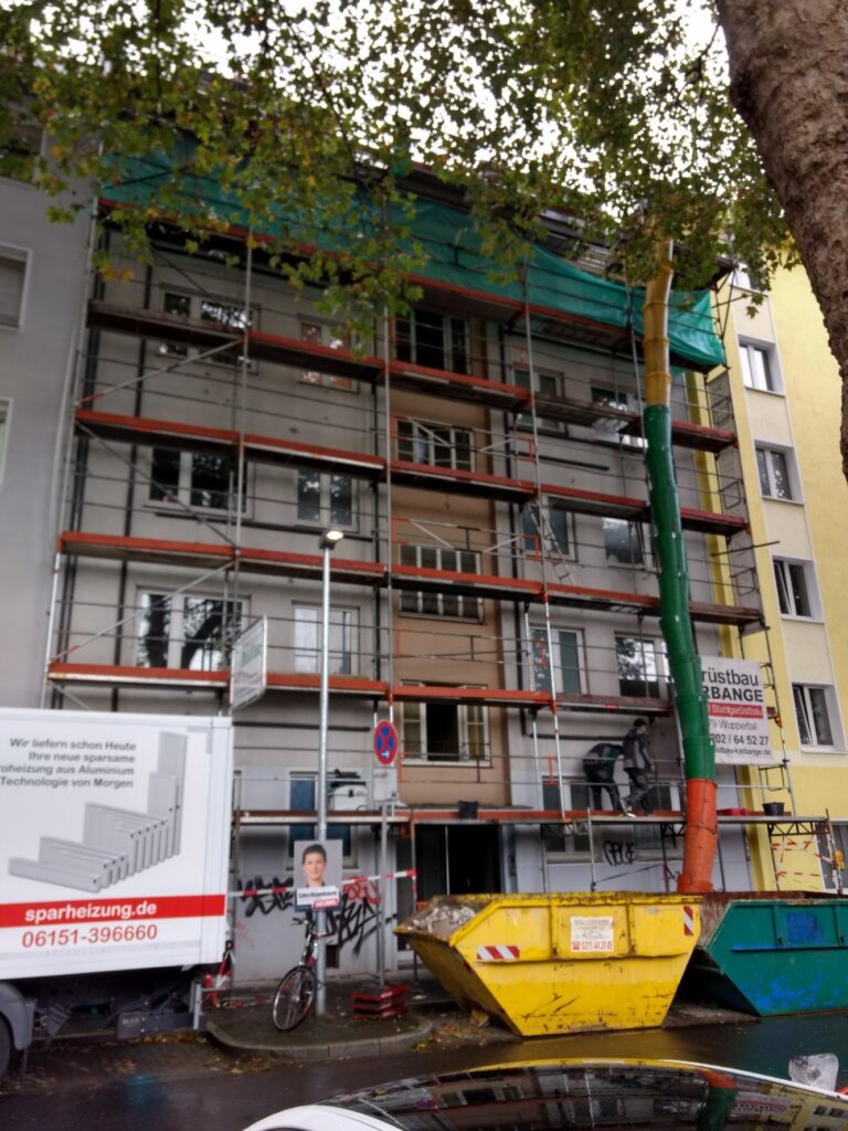 Mehrstöckiges Wohnhaus mit Baugerüst und Containern