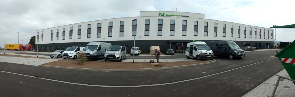 Modernes Hotelgebäude mit geparkten Fahrzeugen davor