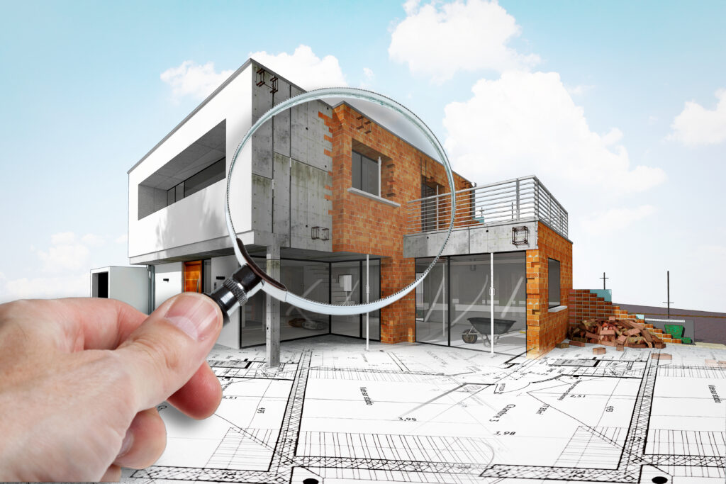 Hausbau mit Bauplan und Lupe betrachtet